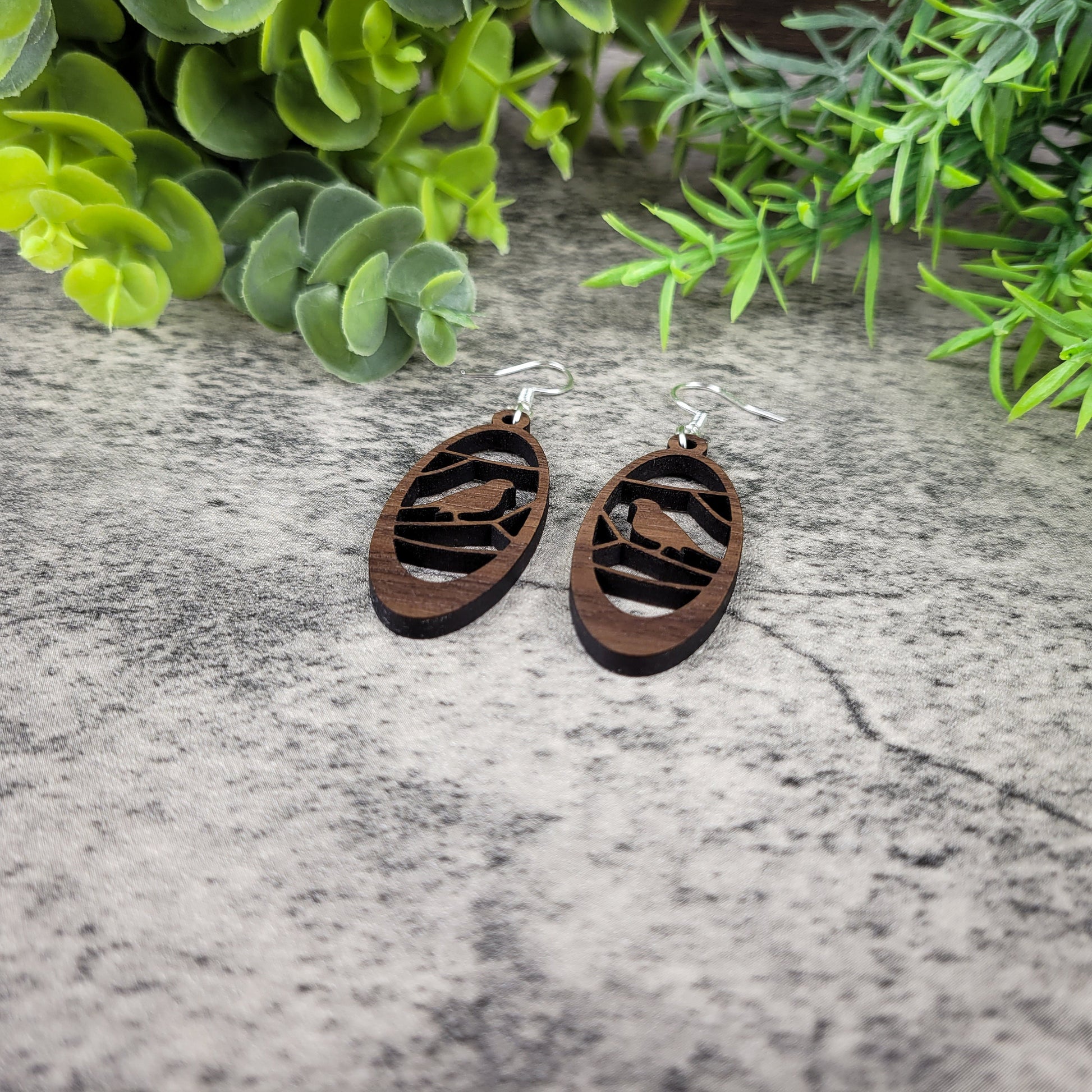 Lightweight walnut wood earrings featuring a bird in branches design on hypoallergenic sterling silver-plated ear wires - flat angled view