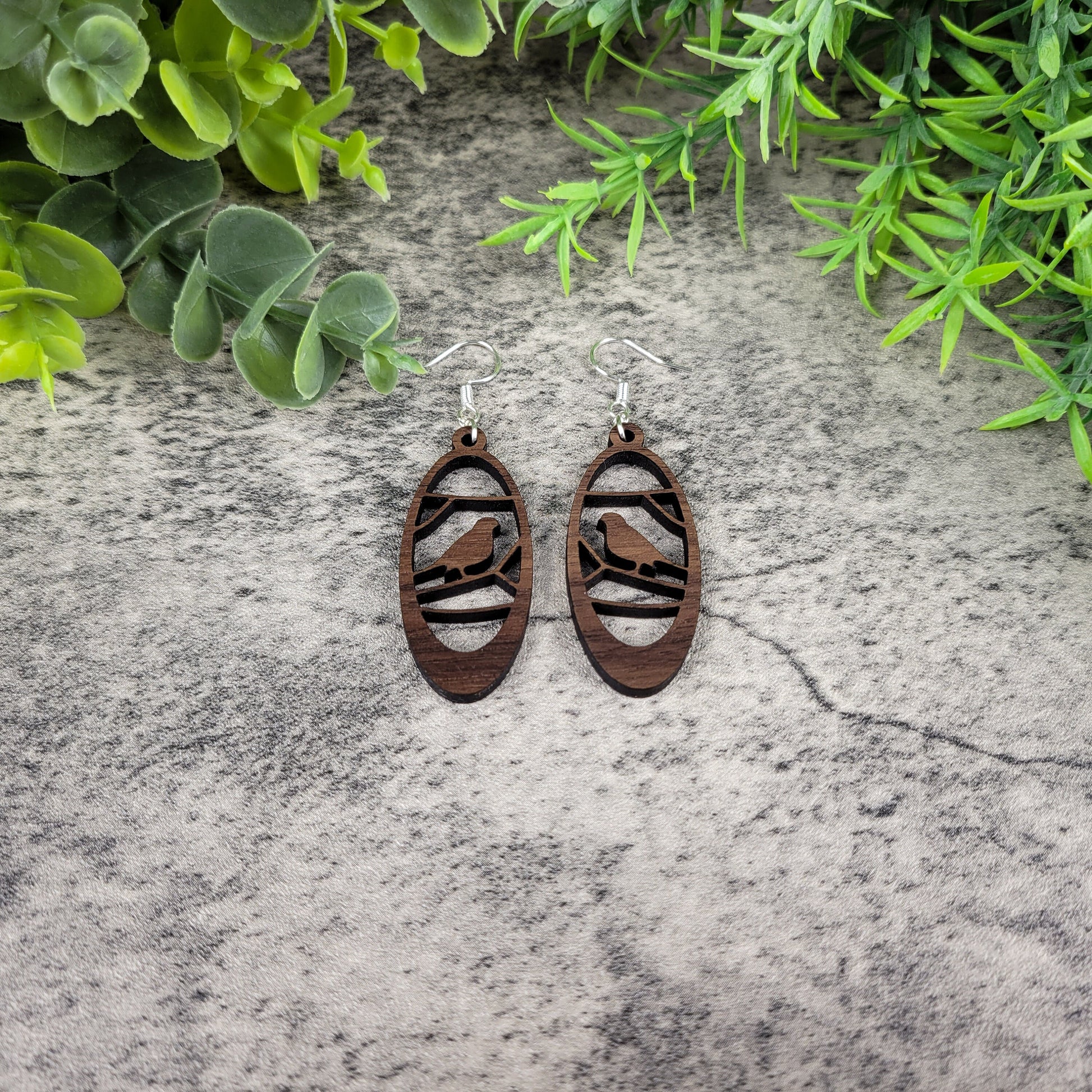 Lightweight walnut wood earrings featuring a bird in branches design on hypoallergenic sterling silver-plated ear wires - flat front view