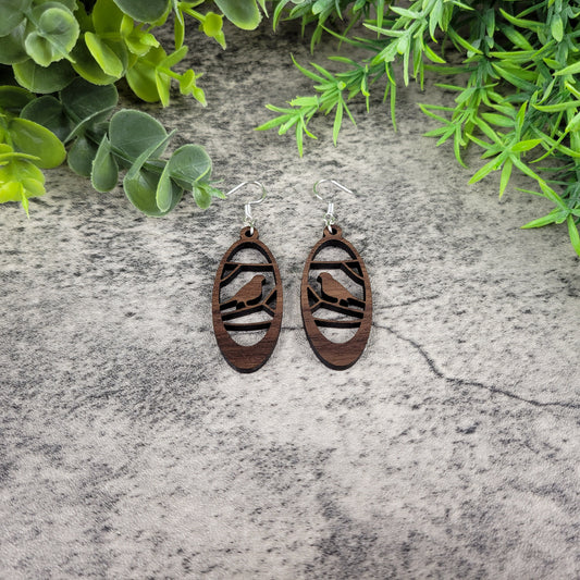 Lightweight walnut wood earrings featuring a bird in branches design on hypoallergenic sterling silver-plated ear wires - flat front view