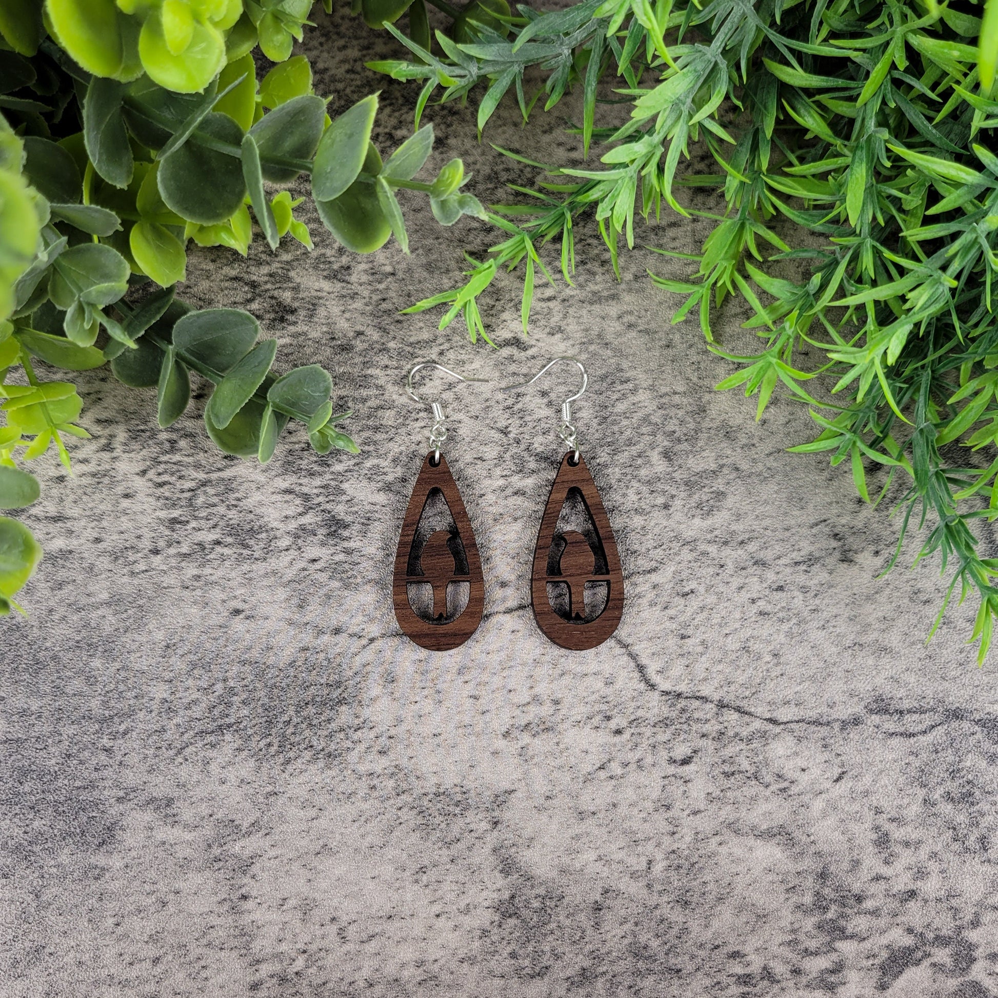 Lightweight walnut wood earrings with bird silhouette design on sterling silver-plated ear wires – on table view