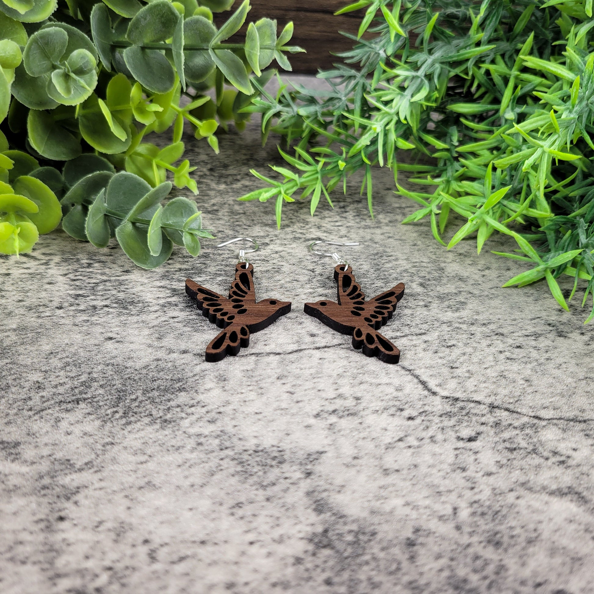 Lightweight walnut wood bird earrings featuring birds in flight design with sterling silver-plated ear wires - angled flat view