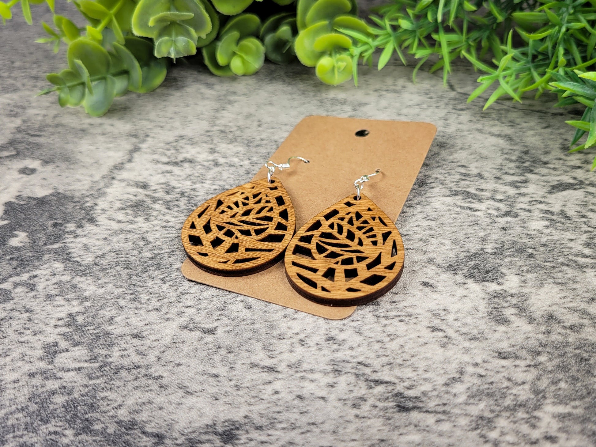 Lightweight botanical teardrop earrings made of laser-cut birch wood with sterling silver-plated hooks – flat left angle view