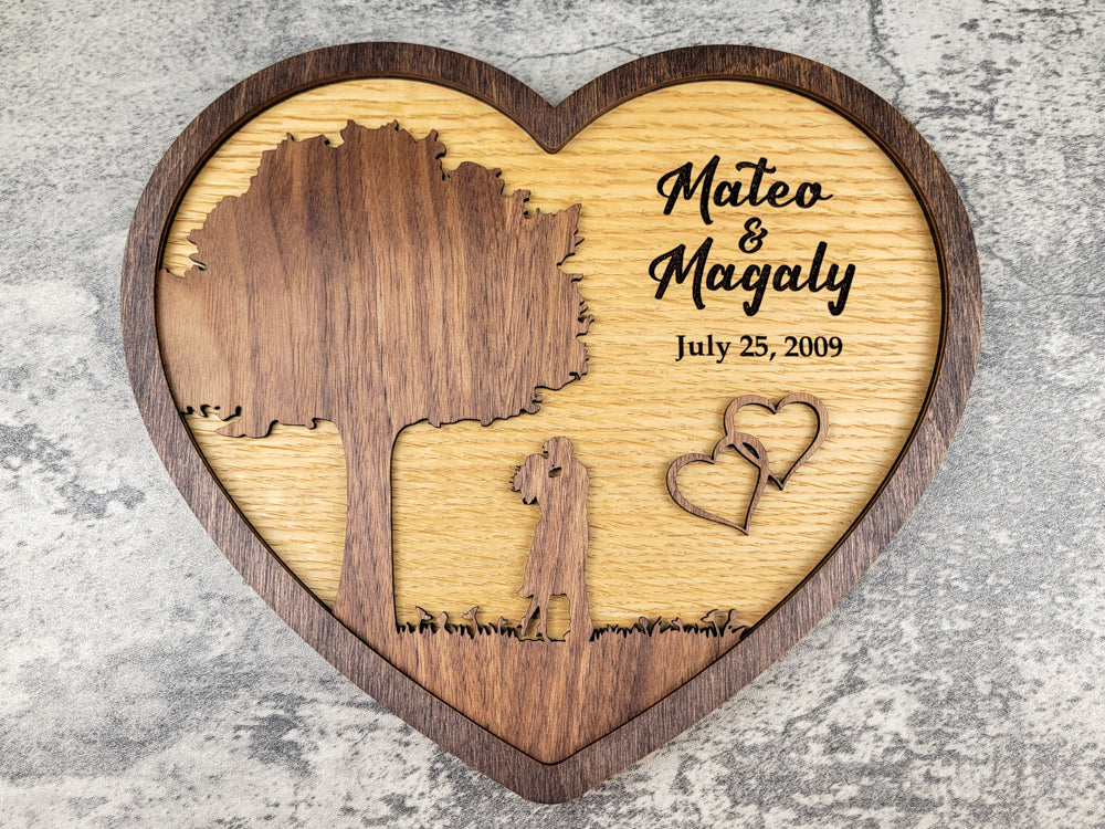 Wooden heart-shaped plaque with engraved names and date on a textured surface