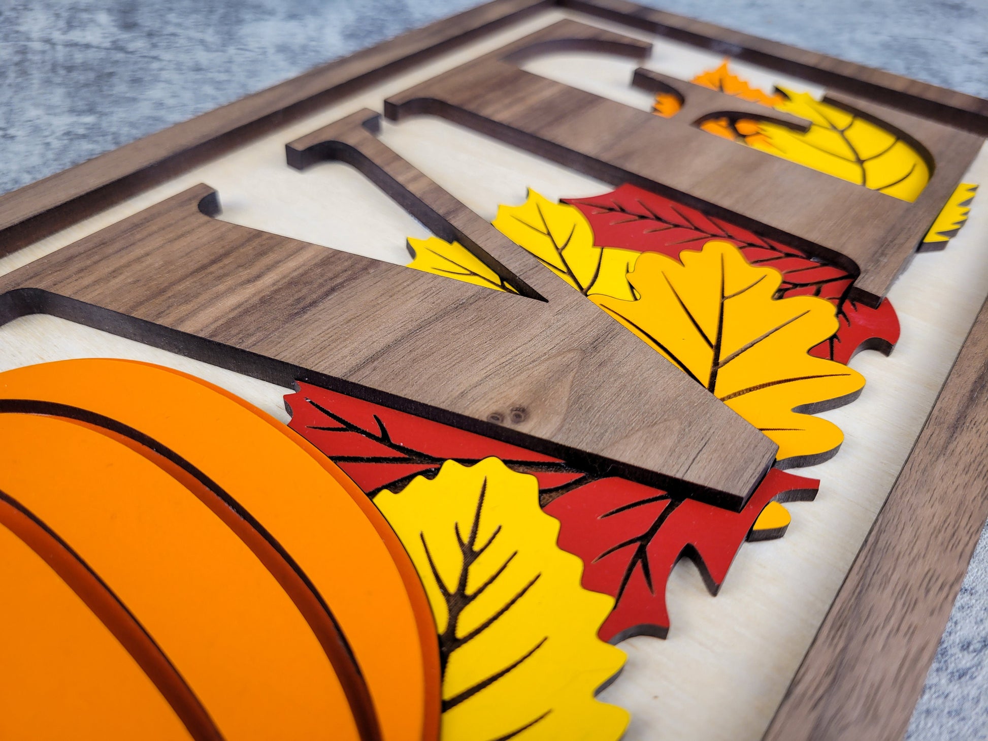 Wooden letter 'VE' with autumn leaf decorations on a wooden surface