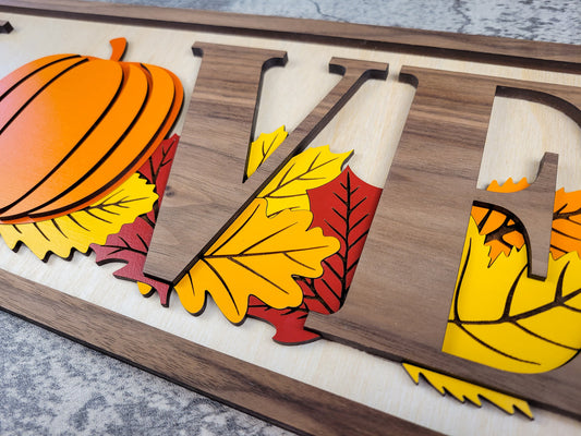 Wooden sign with letters, pumpkins, and leaves on a textured surface