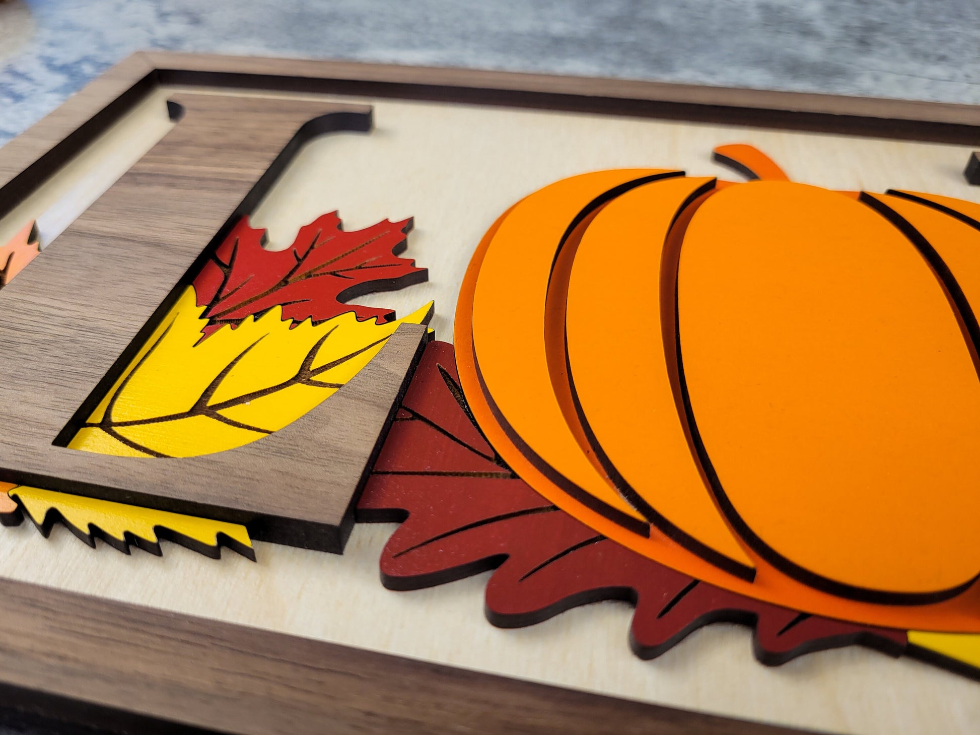 Wooden cutout with pumpkins and leaves on a wooden surface