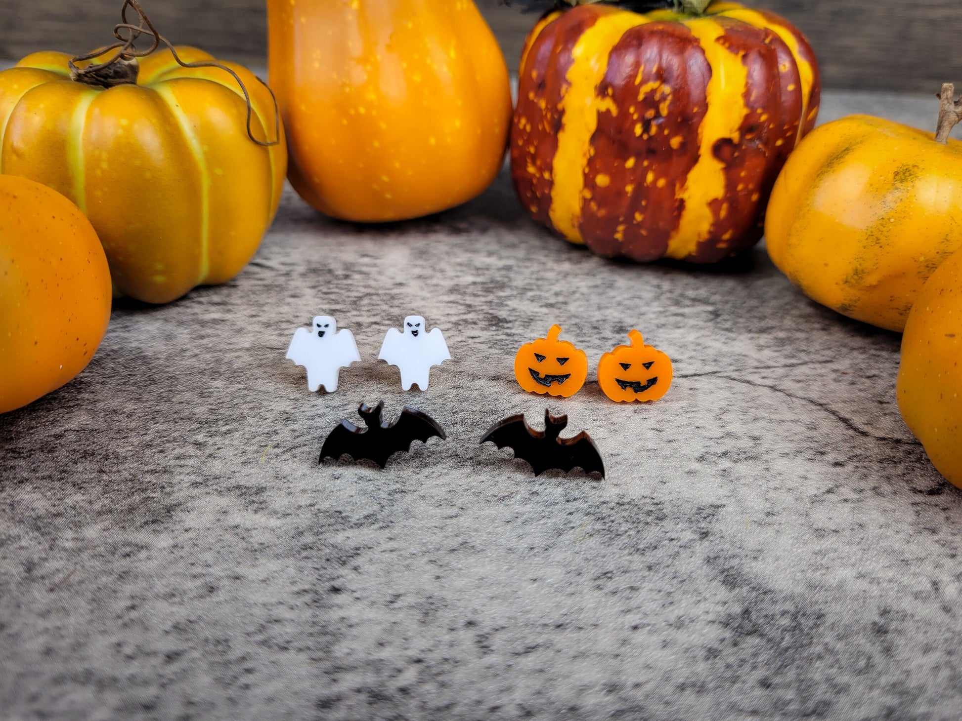 Halloween jewelry collection with ghost, bat, and pumpkin earrings close up view