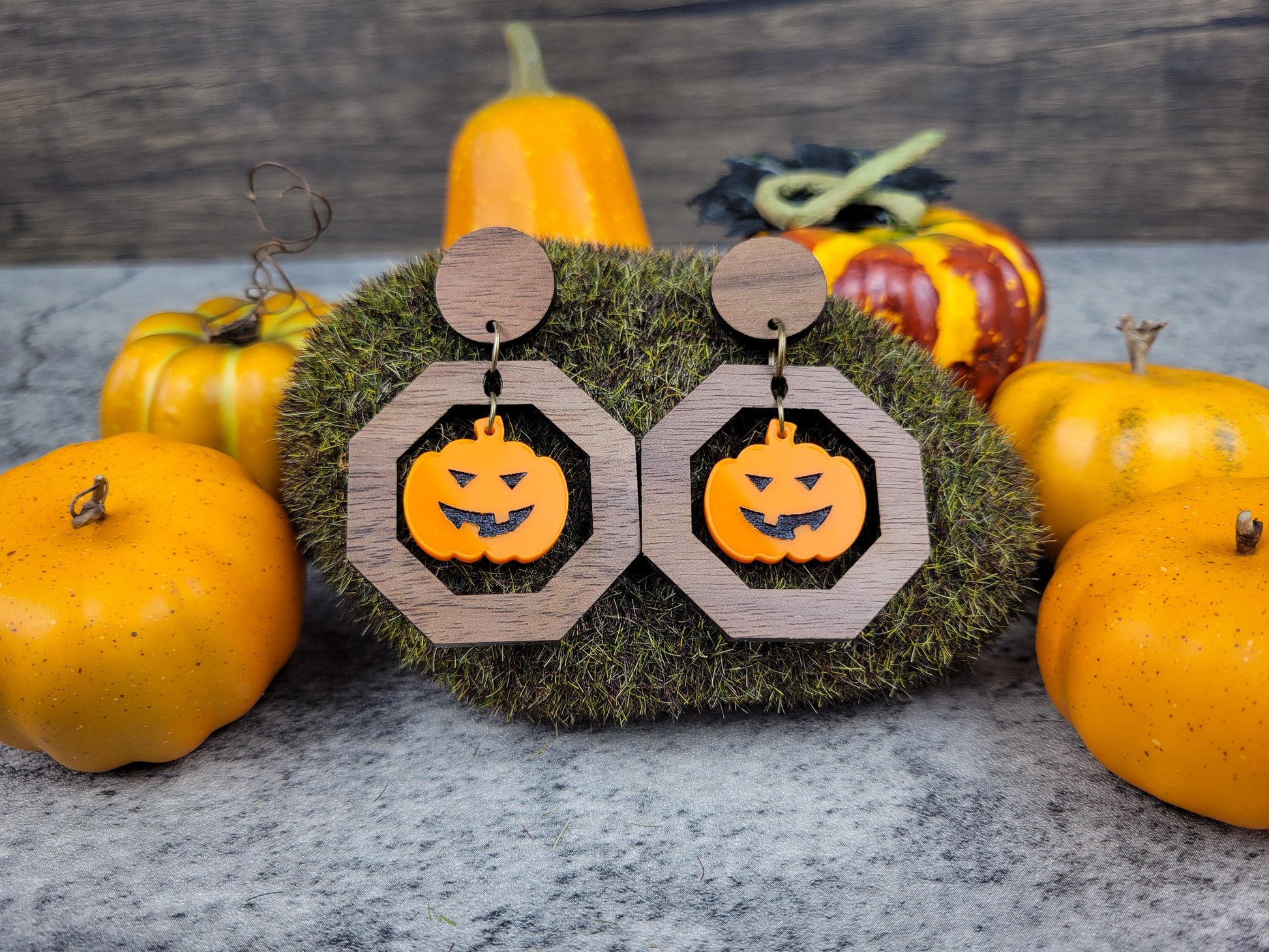 Jack-O-Lantern geometric dangle earrings with walnut studs and acrylic pumpkin on a fall background