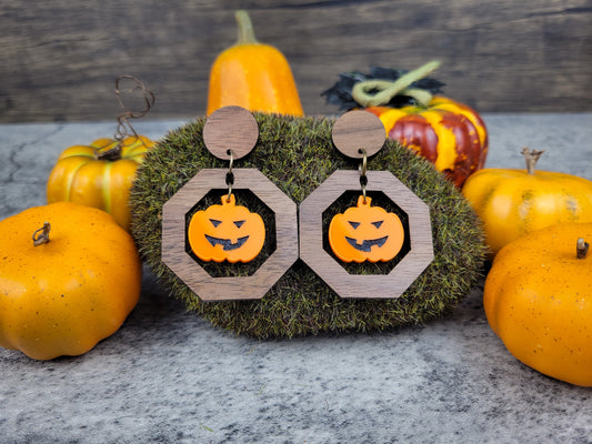 Jack-O-Lantern geometric dangle earrings with walnut studs and acrylic pumpkin on a fall background