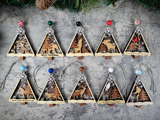 Set of triangular wooden Christmas tree ornaments with nature-themed designs on a textured surface.