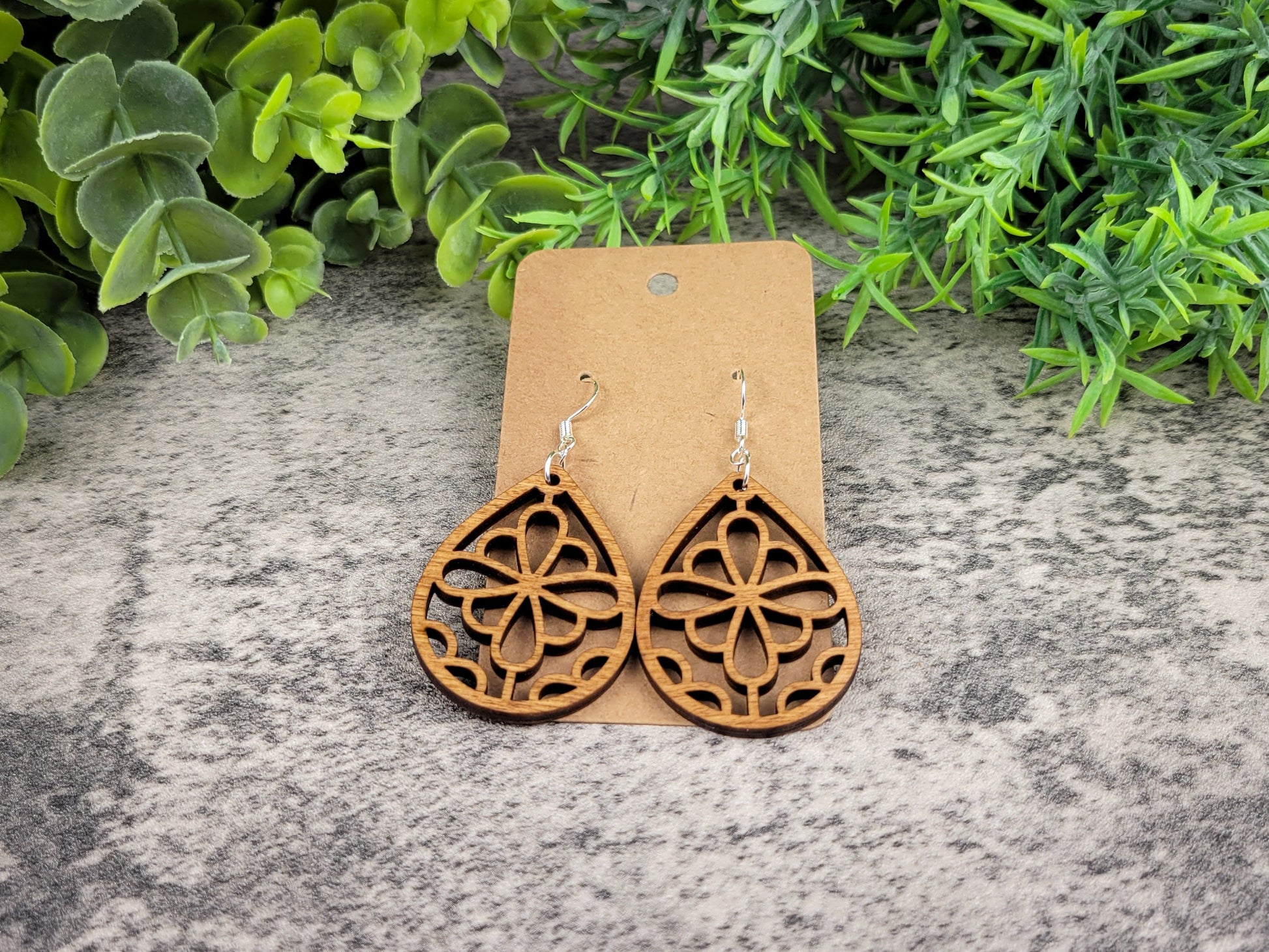 Laser-cut wooden summer flower teardrop earrings with silver ear wires – low angle view