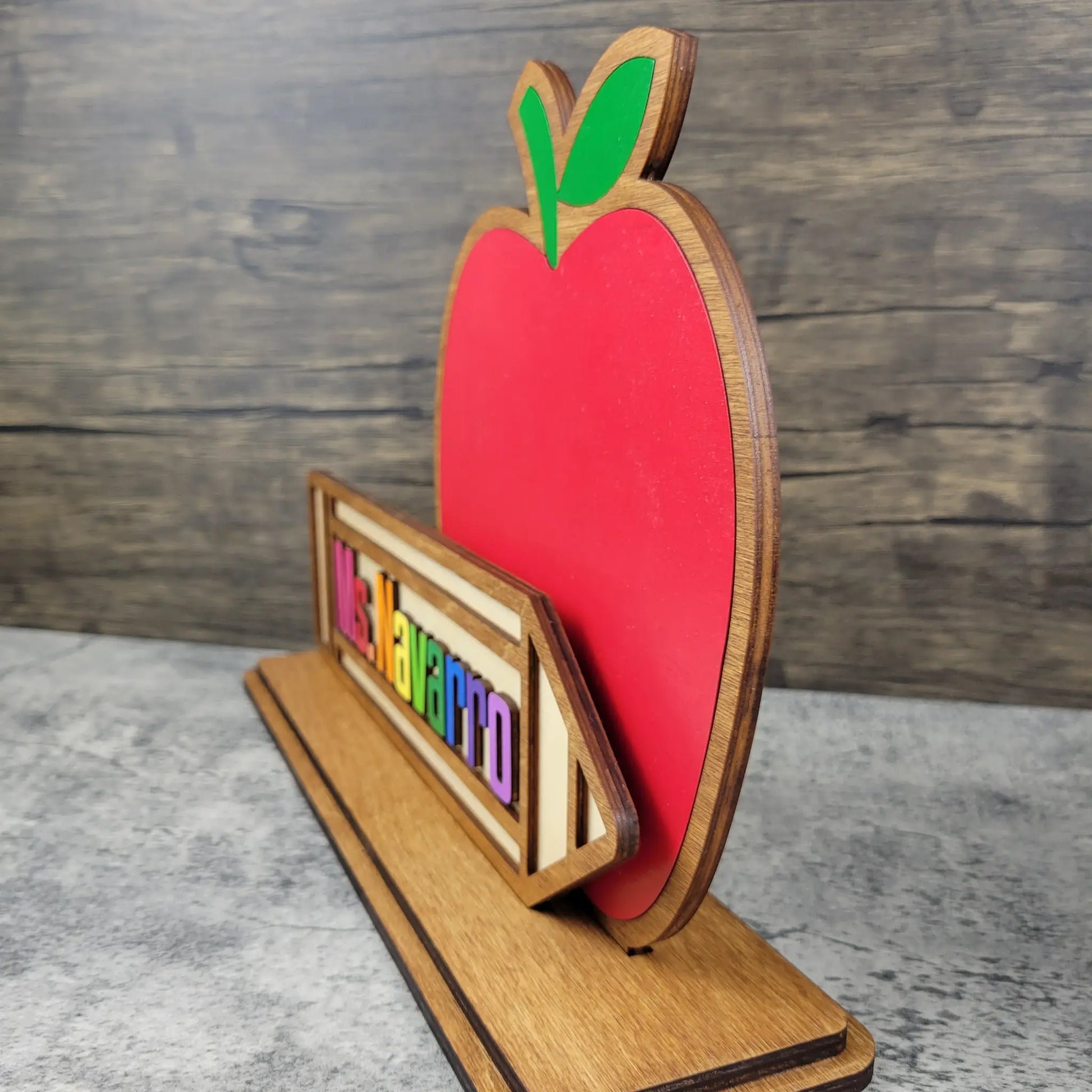 Wooden apple-shaped sign with colorful letters on a wooden background