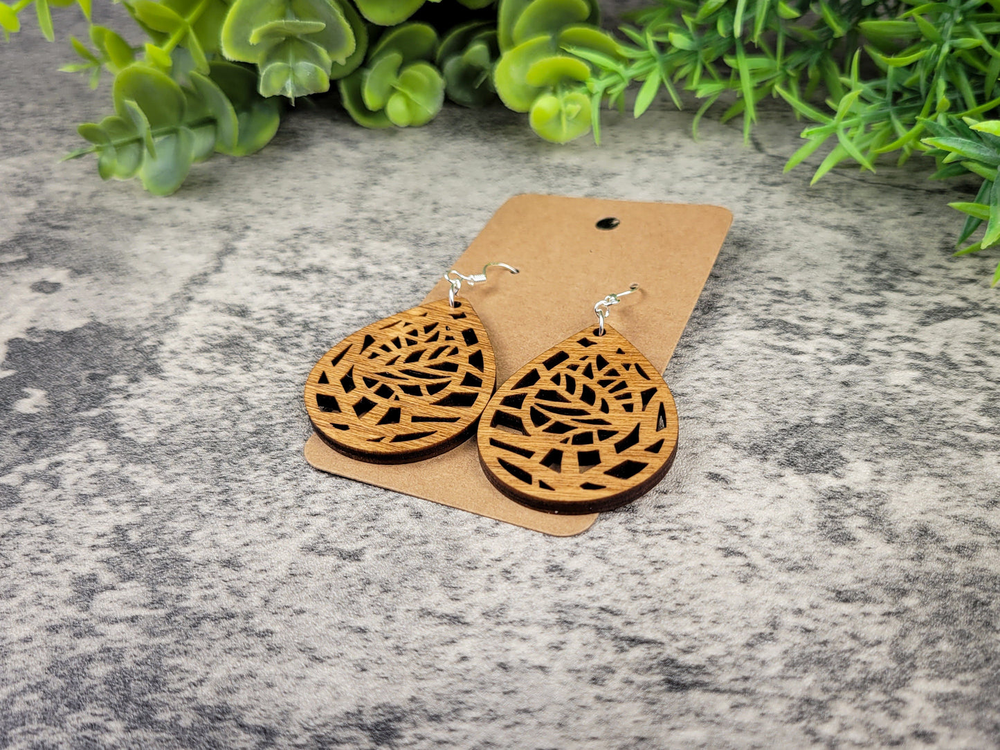Lightweight botanical teardrop earrings made of laser-cut birch wood with sterling silver-plated hooks – flat left angle view