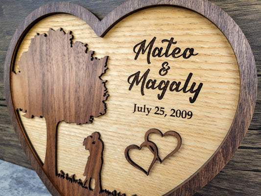 Wooden heart-shaped plaque with engraved names and dates on a wooden background