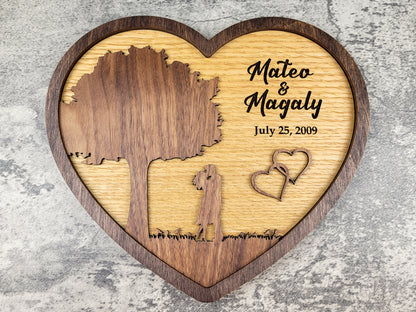 Wooden heart-shaped plaque with engraved names and date on a textured surface