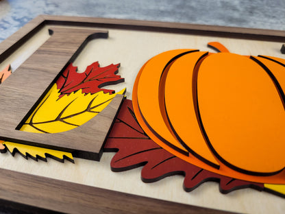 Wooden cutout with pumpkins and leaves on a wooden surface