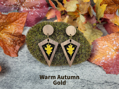 Wooden earrings with leaf design on a moss ball and autumn leaves background